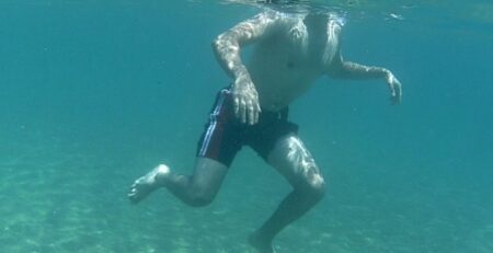 Denizde derinde su üzerinde duran Teo sport yüzme kursu erkek öğrencisi